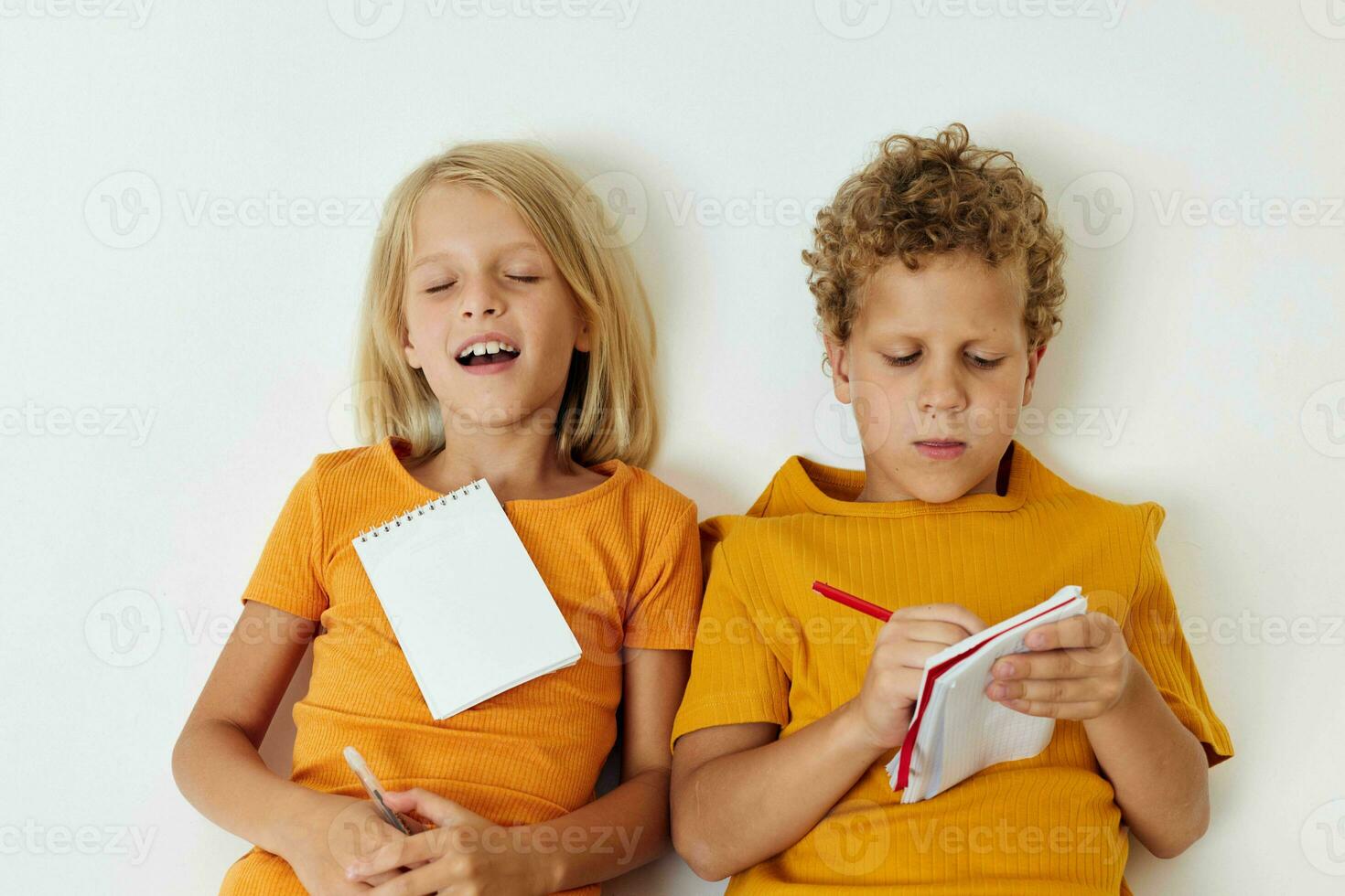 two joyful children lie on the floor with notepads and pencils childhood lifestyle unaltered photo