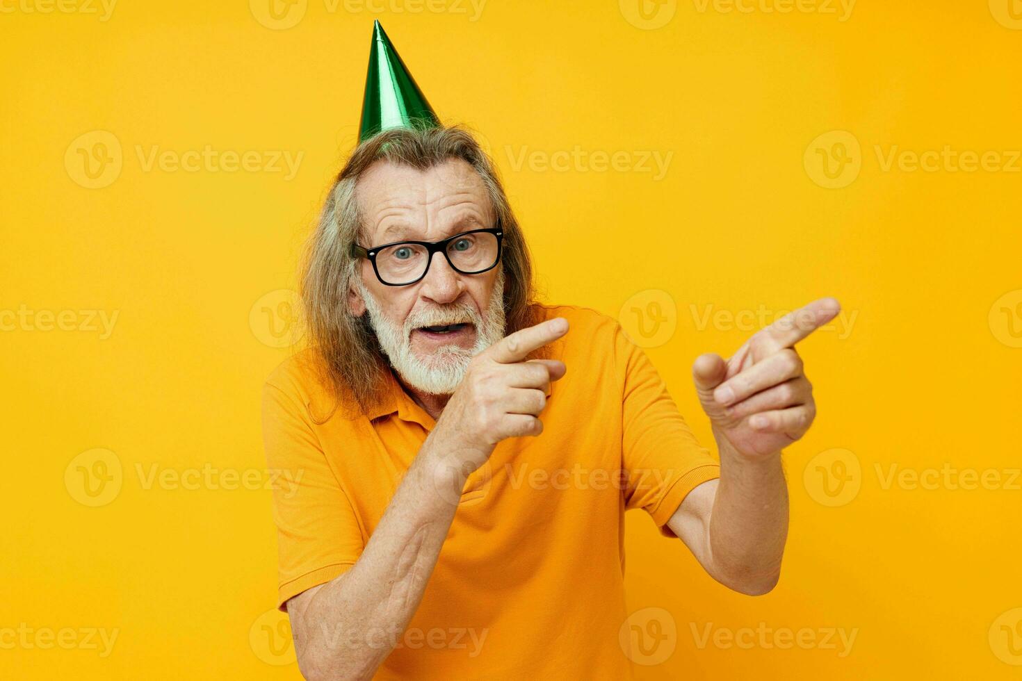 Senior grey-haired man wearing glasses green cap on his head holiday emotions yellow background photo