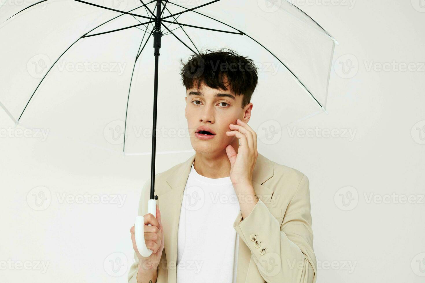 nice young guy with an open umbrella in a suit light background photo