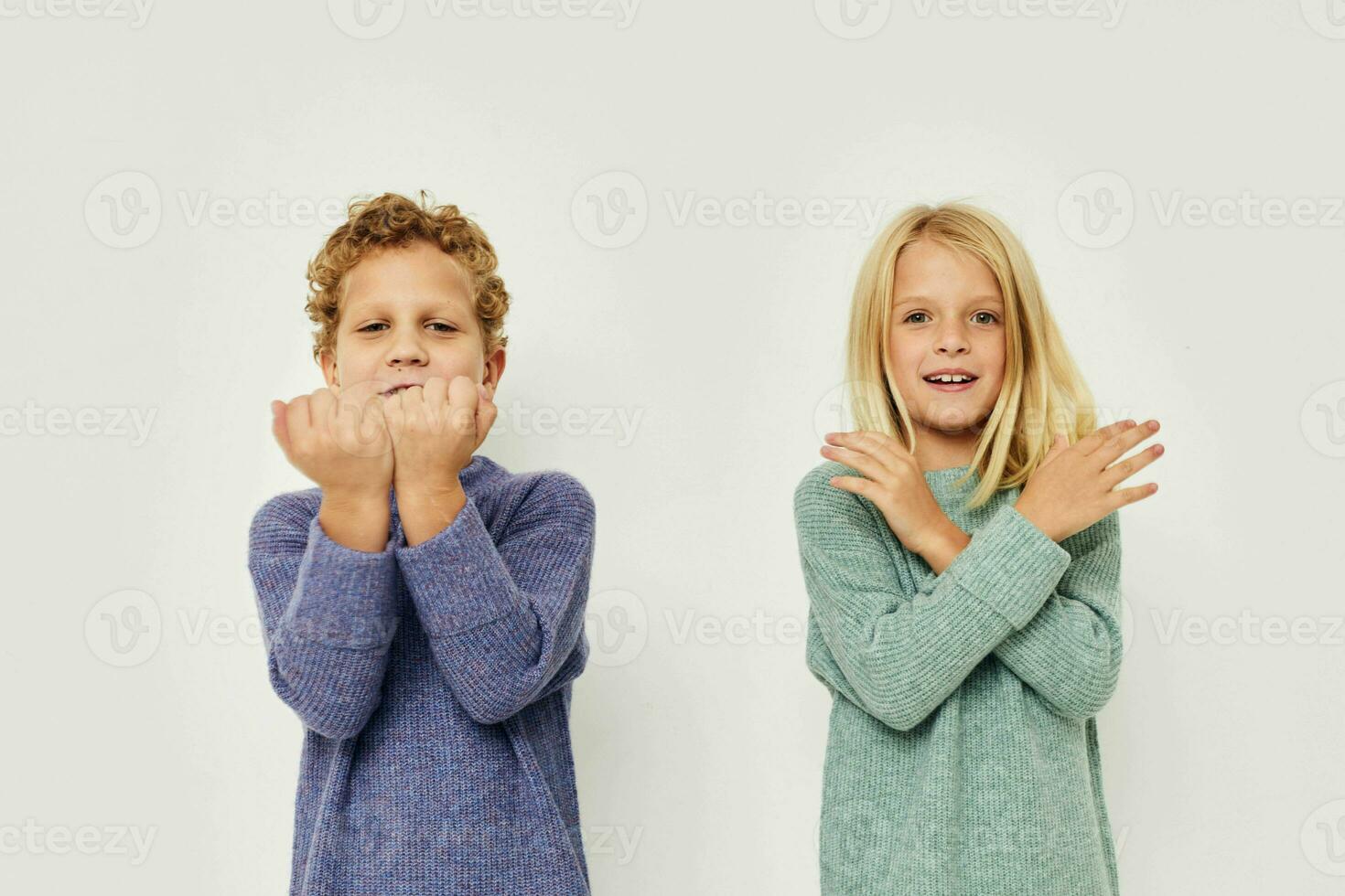 Little boy and girl in multi-colored sweaters posing for fun light background photo