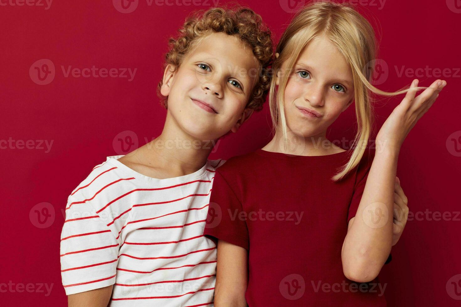 Small children emotions stand side by side in everyday clothes red background unaltered photo