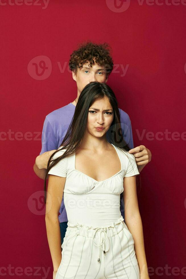 a guy stands behind a girl and holds her hair red background photo