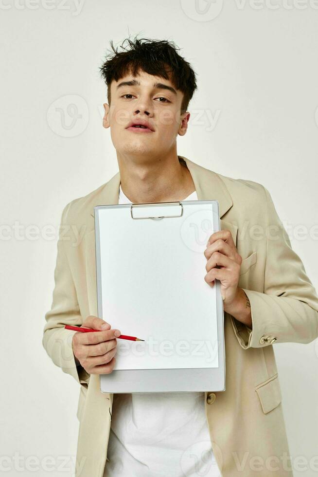 portrait of a young man in a beige suit copy-space notebook light background unaltered photo