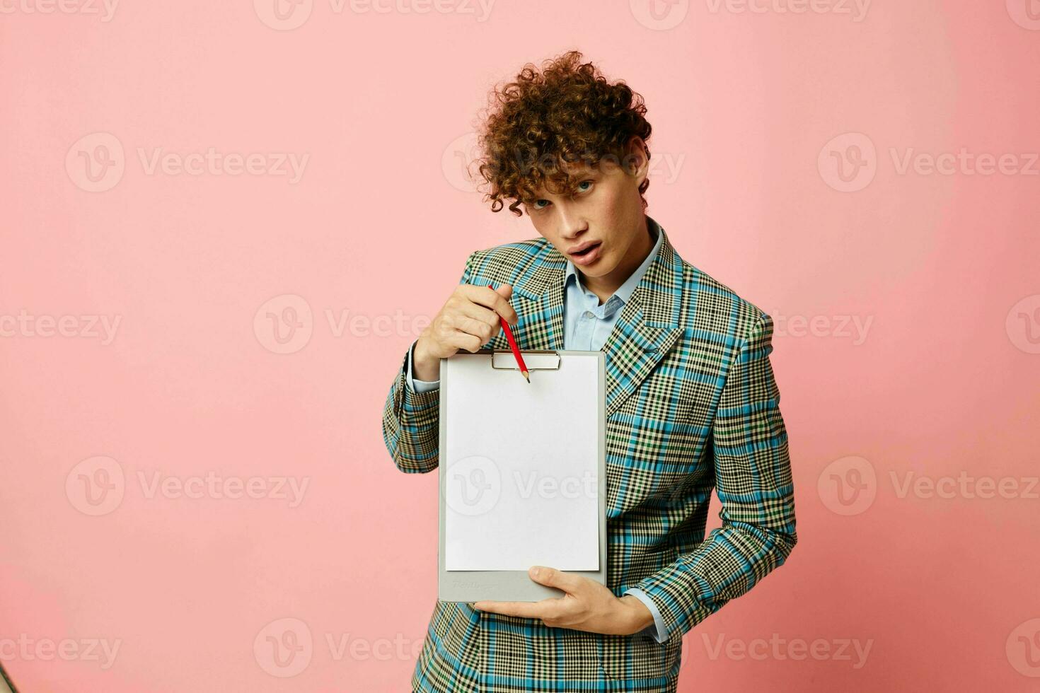 portrait of a young curly man in a business suit copy-space documents pink background unaltered photo
