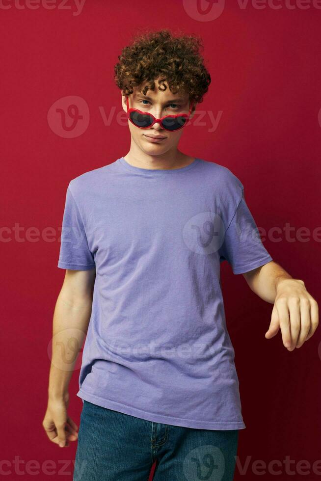 Young curly-haired man hand gestures heart shaped glasses posing isolated background photo