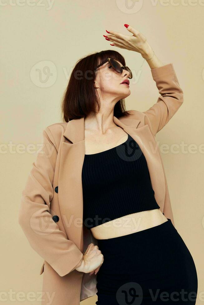 attractive woman in a beige jacket elegant style sunglasses light background photo