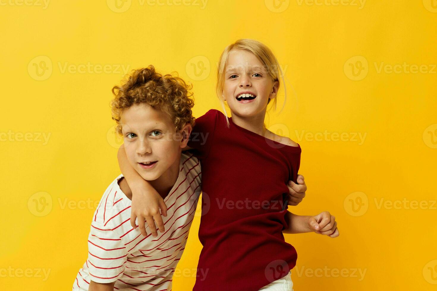 Boy and girl standing side by side posing childhood emotions on colored background photo