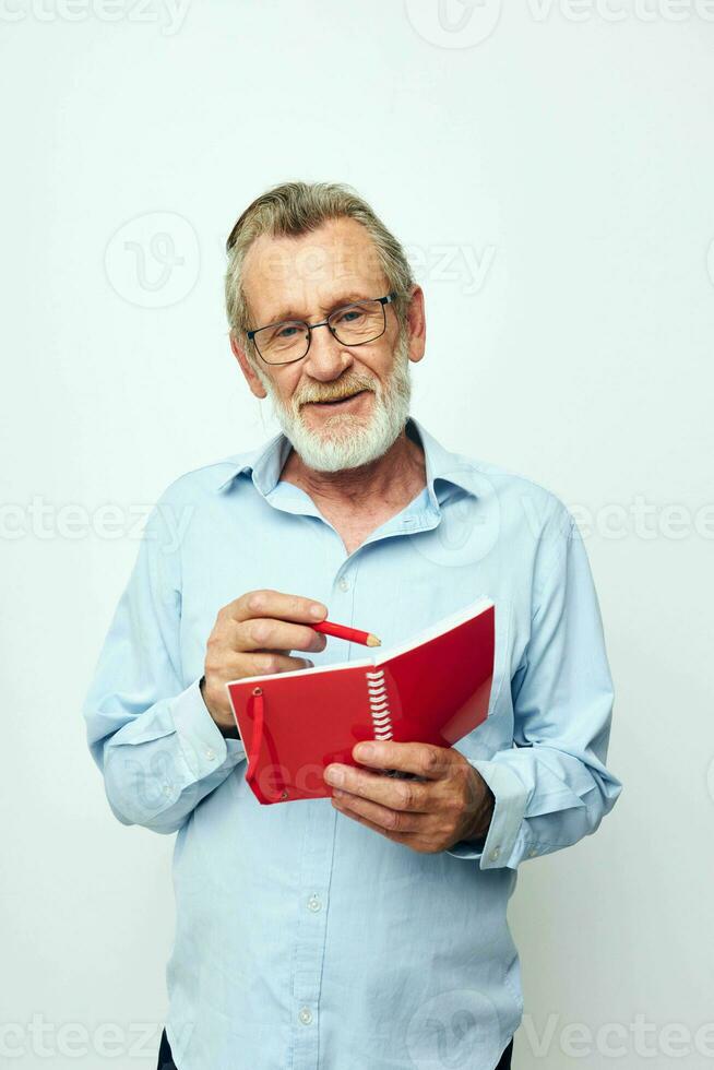 Portrait of happy senior man with red notebook and pen light background photo