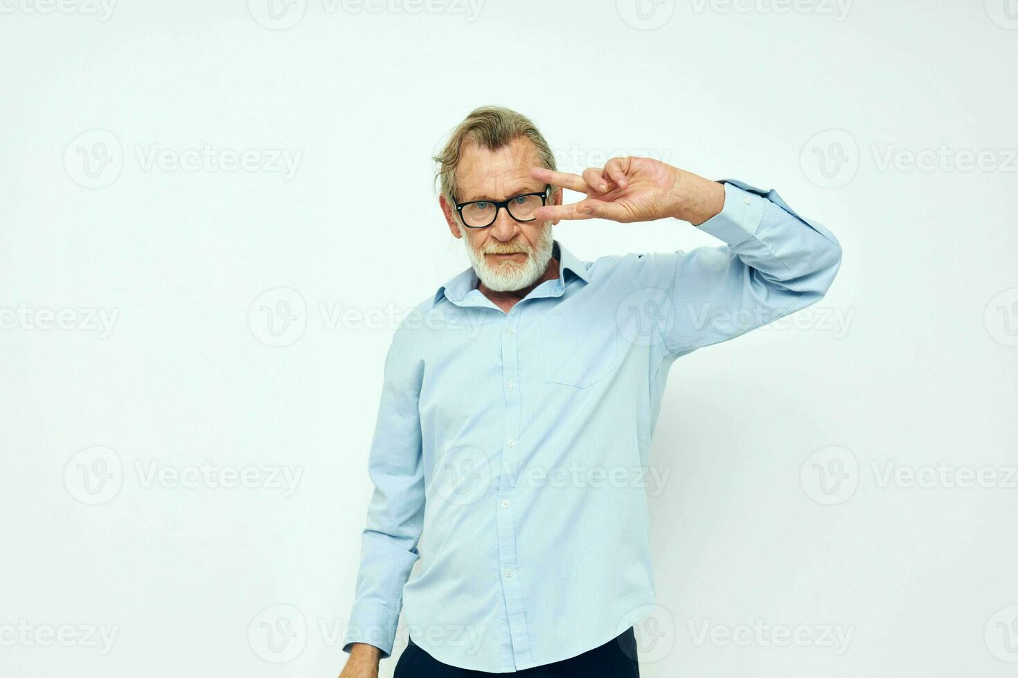 retrato de contento mayor hombre en azul camisas gestos con su manos ligero antecedentes foto