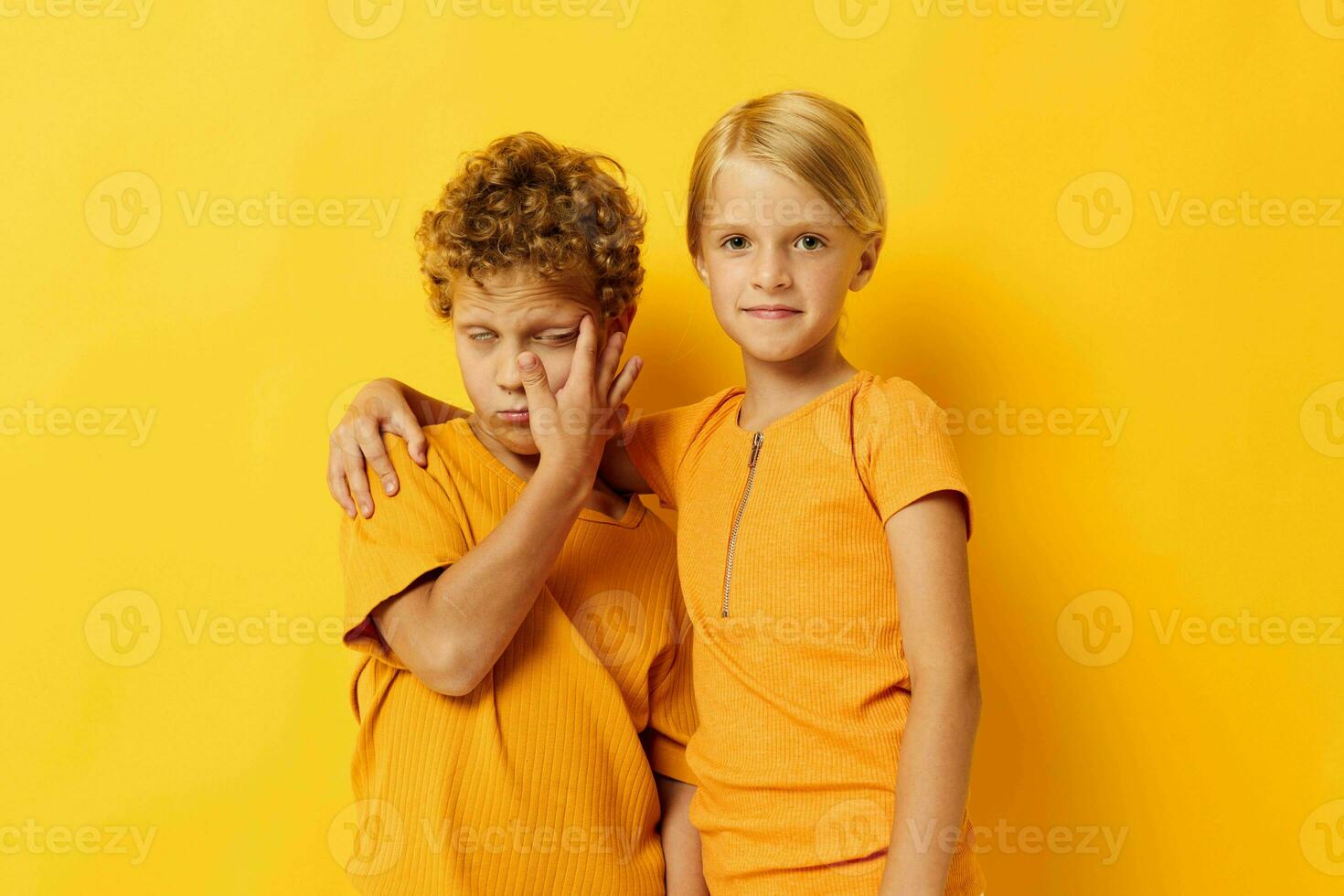 cheerful children in yellow t-shirts standing side by side childhood emotions yellow background unaltered photo