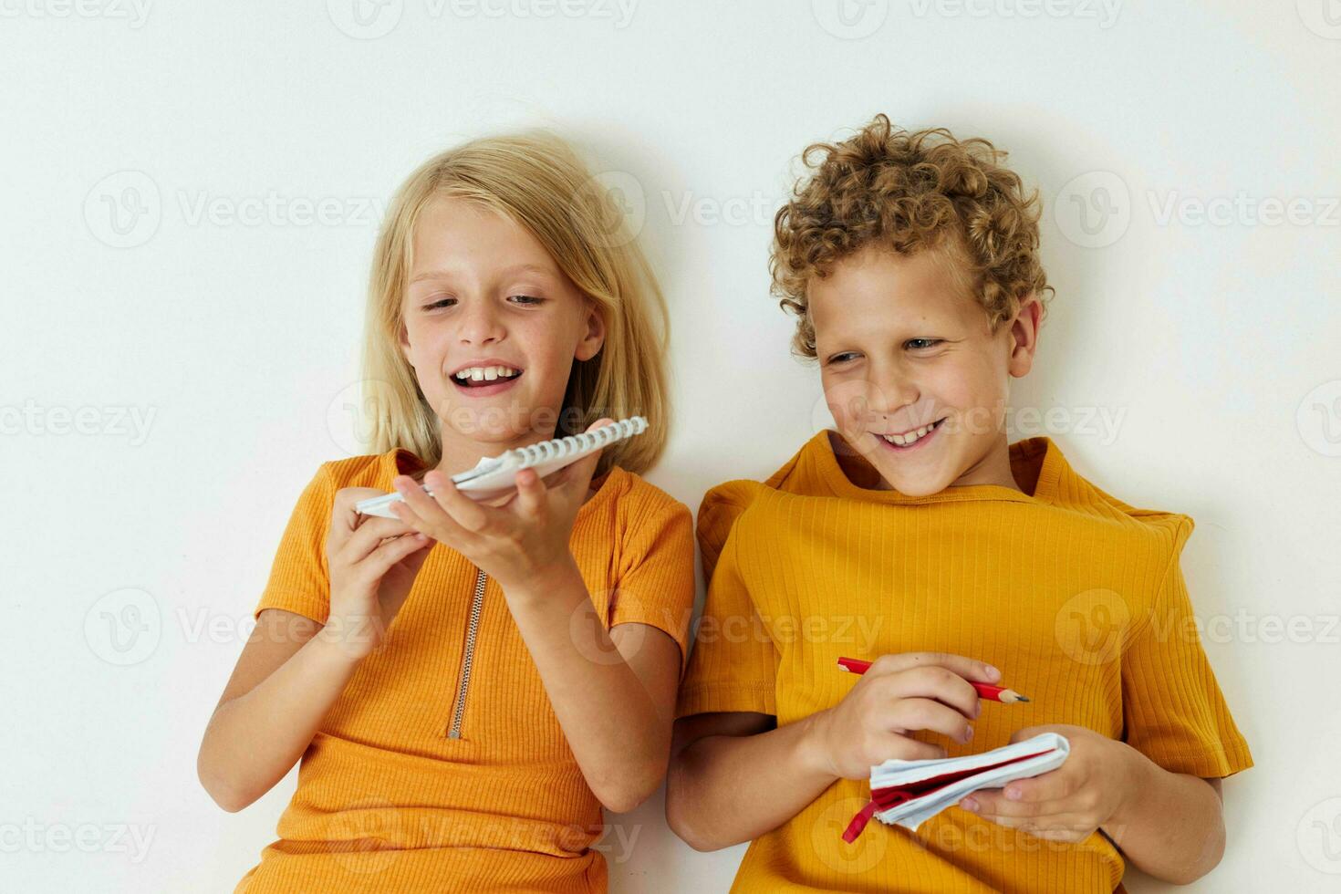 Boy and girl lie on the floor with notepads and pencils childhood lifestyle unaltered photo