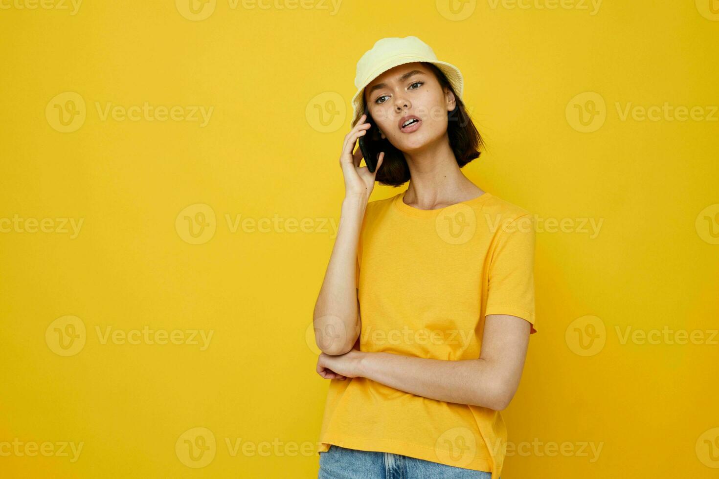 optimista joven mujer amarillo camiseta y sombrero verano estilo con teléfono estilo de vida inalterado foto