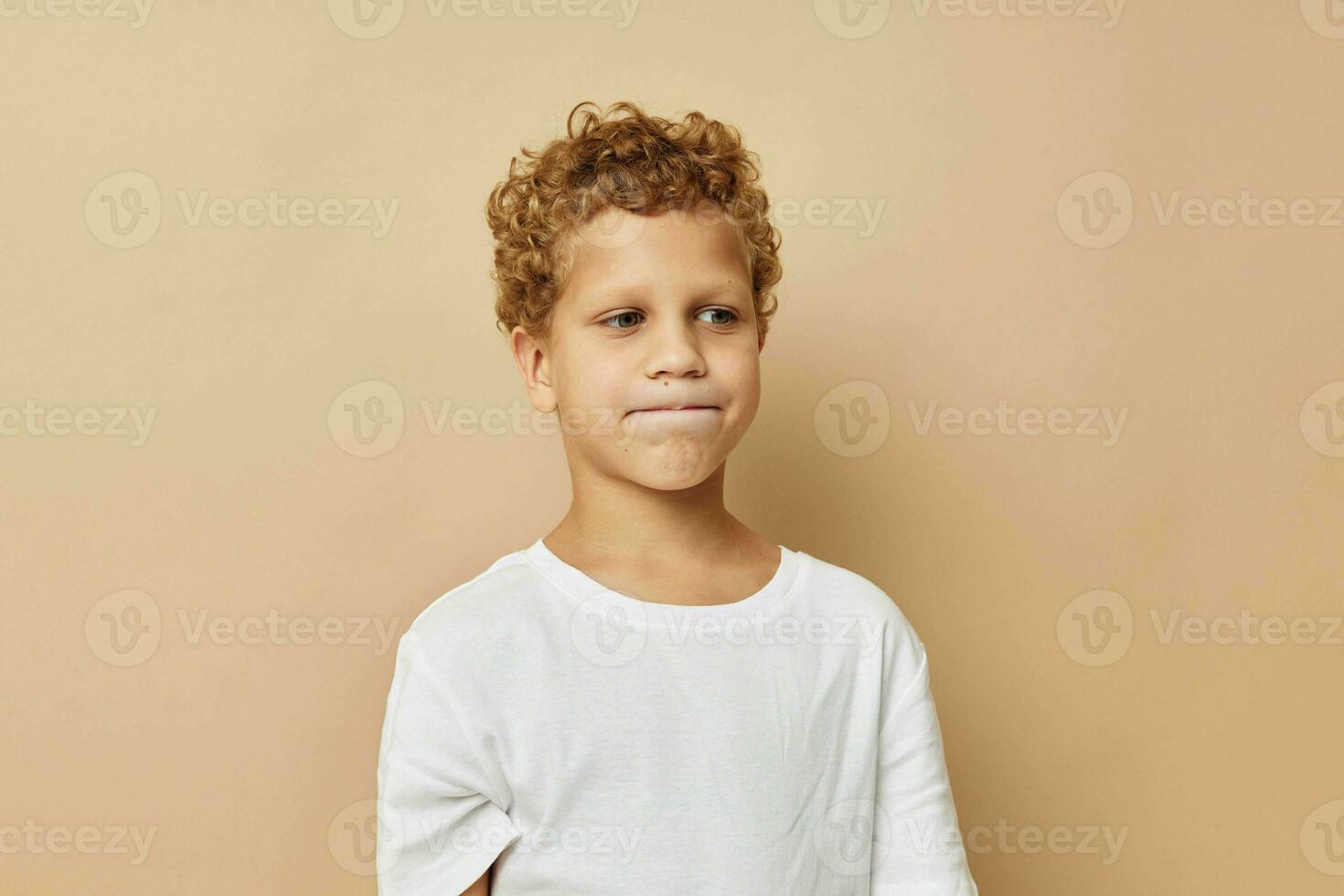 chico con Rizado pelo en un blanco camiseta posando foto