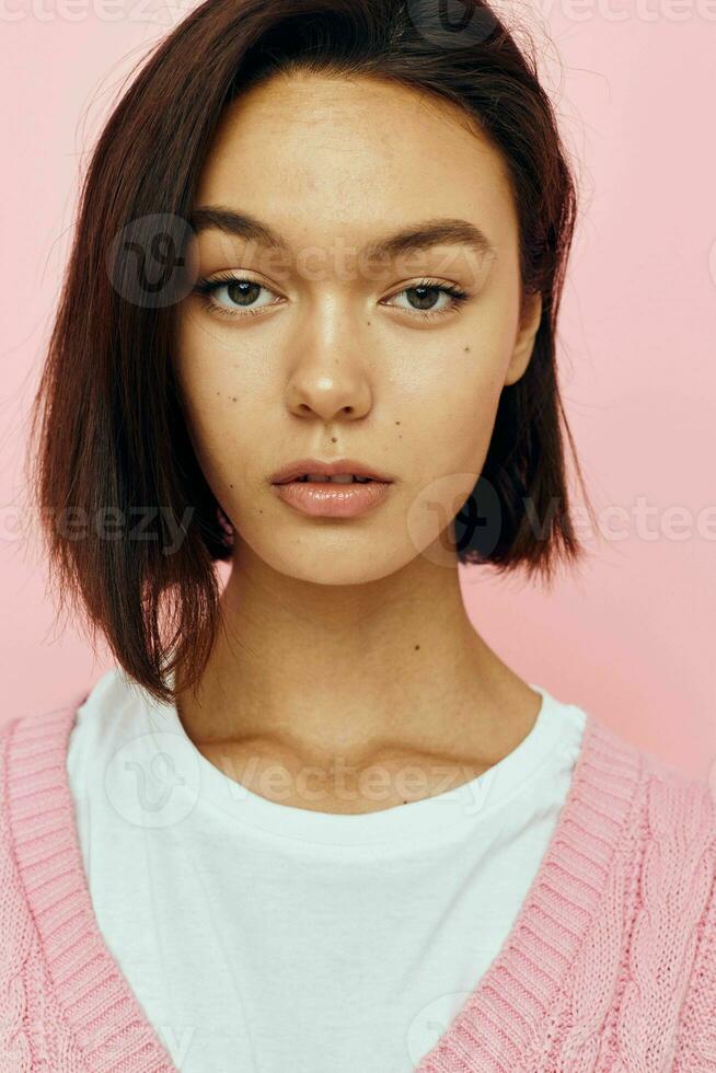 Young woman with short hair and a pink sweater isolated background photo