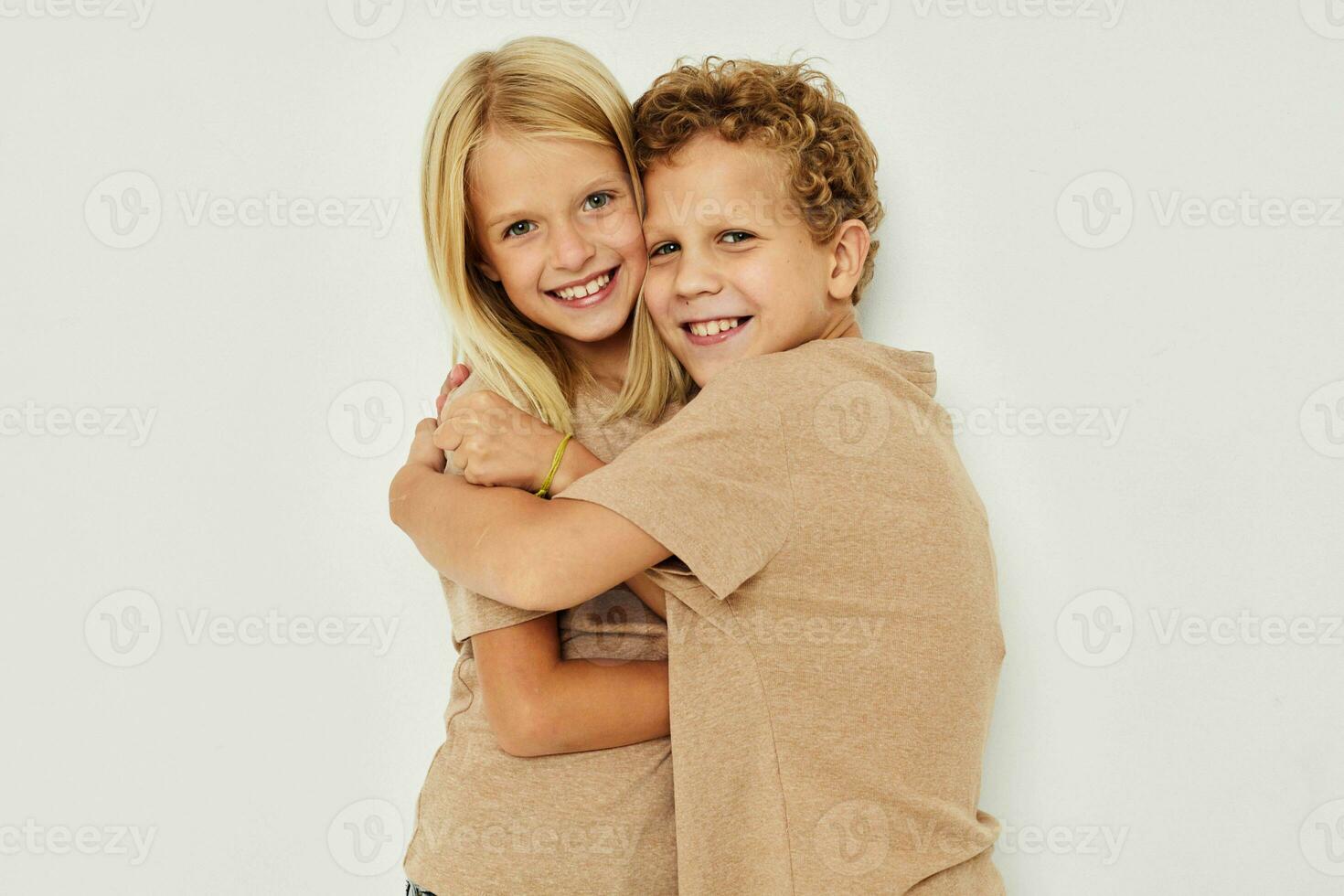 Portrait of cute children in beige t-shirts posing for fun isolated background photo