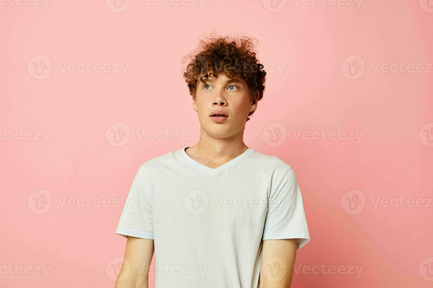 Young curly-haired man summer clothes white tshirt posing isolated background unaltered photo