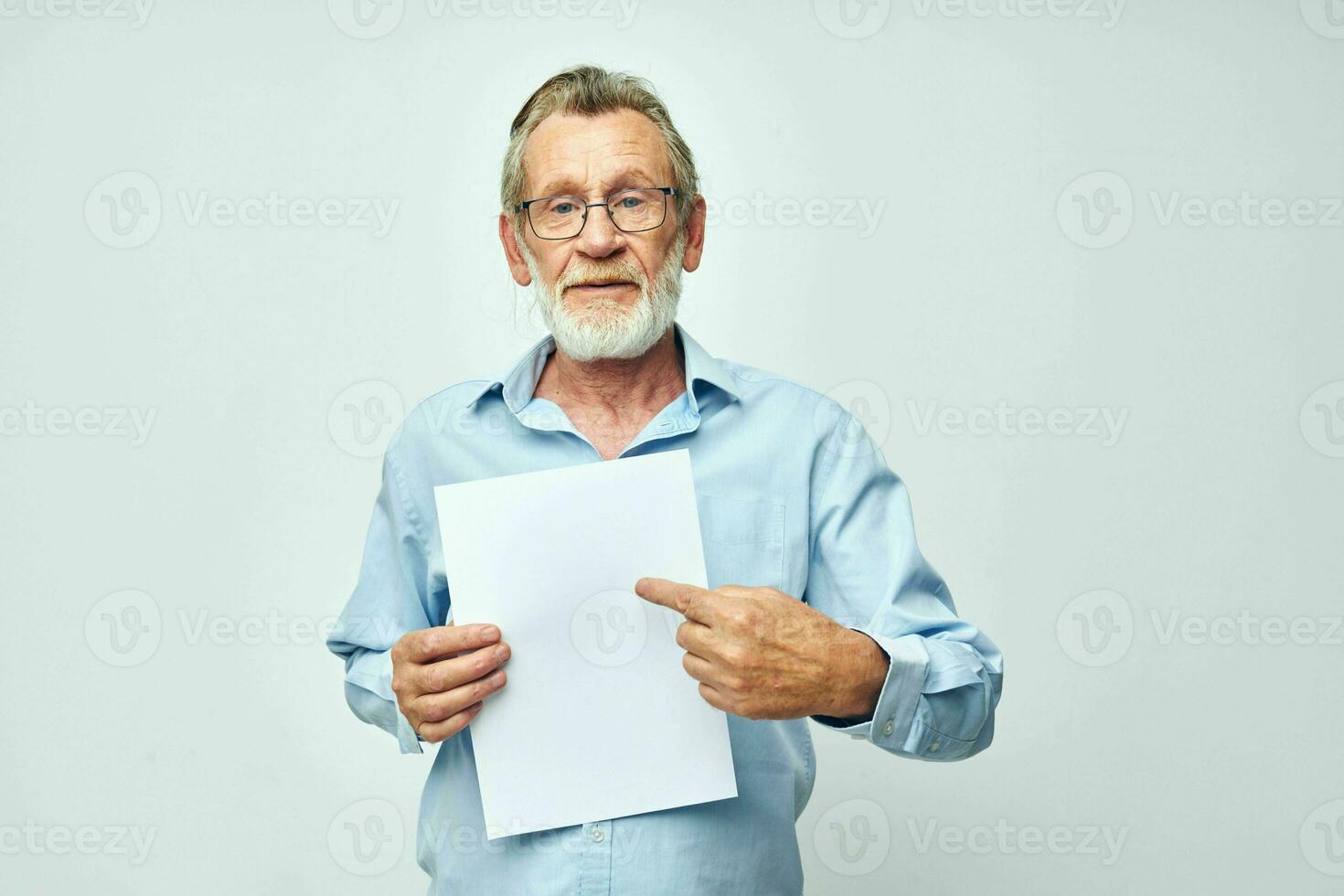Senior grey-haired man blank sheet of paper gesture hands smile light background photo