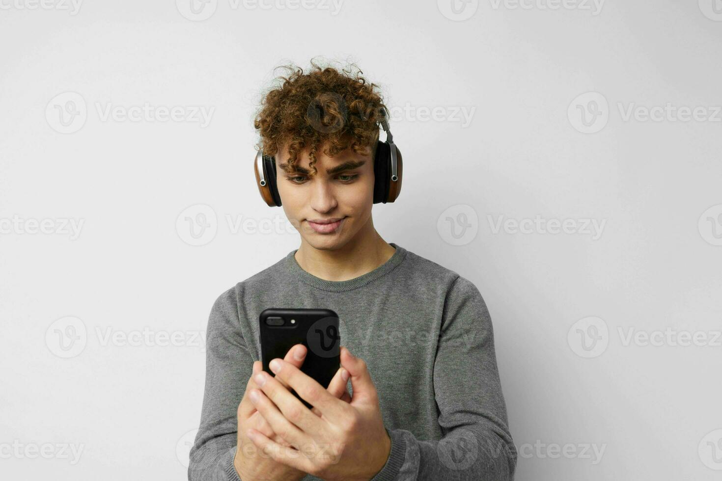 Attractive man with a phone in hand listening to music in headphones light background photo