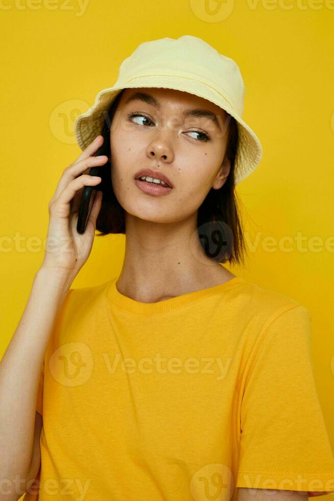 optimistic young woman yellow t-shirt and Hat summer style with phone Lifestyle unaltered photo