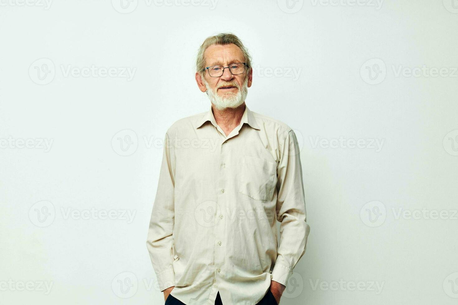 An old man stands on a gray background and looks at the camera with glasses photo