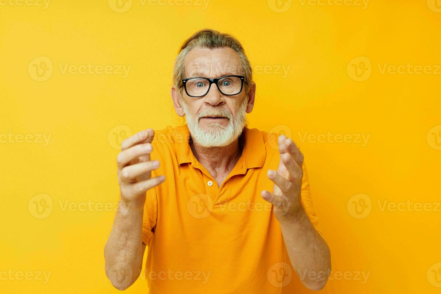 Senior grey-haired man wearing glasses yellow shirt posing isolated background photo