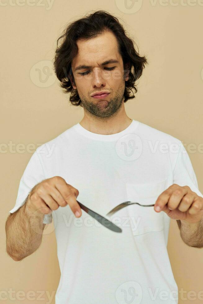 Attractive man in a white T-shirt with knife with fork isolated background photo