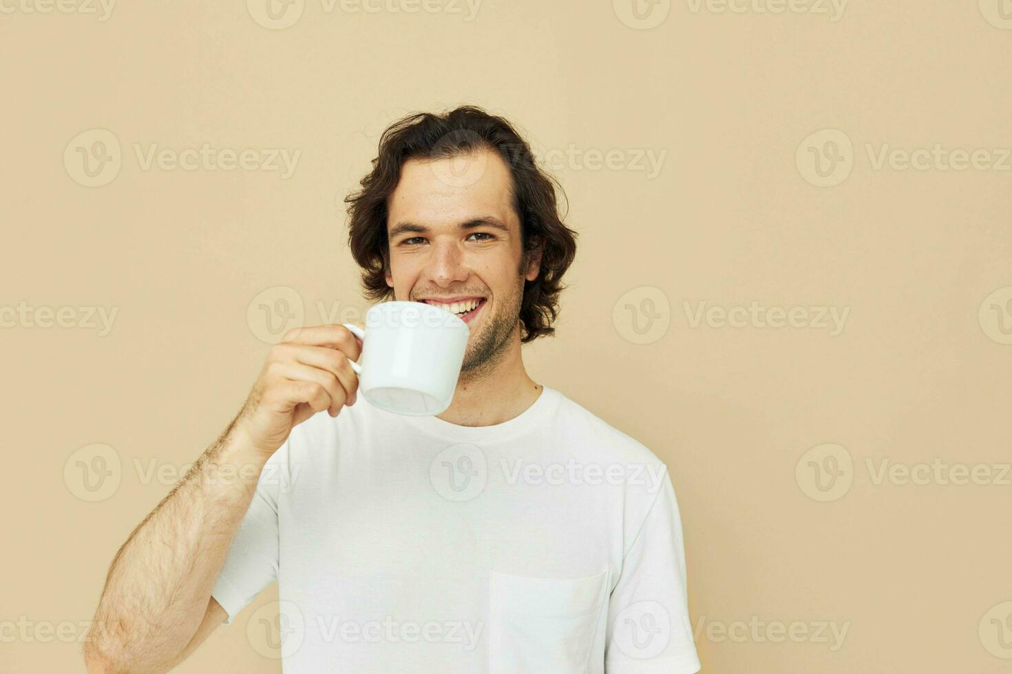 handsome man with a white mug in his hands emotions posing beige background photo