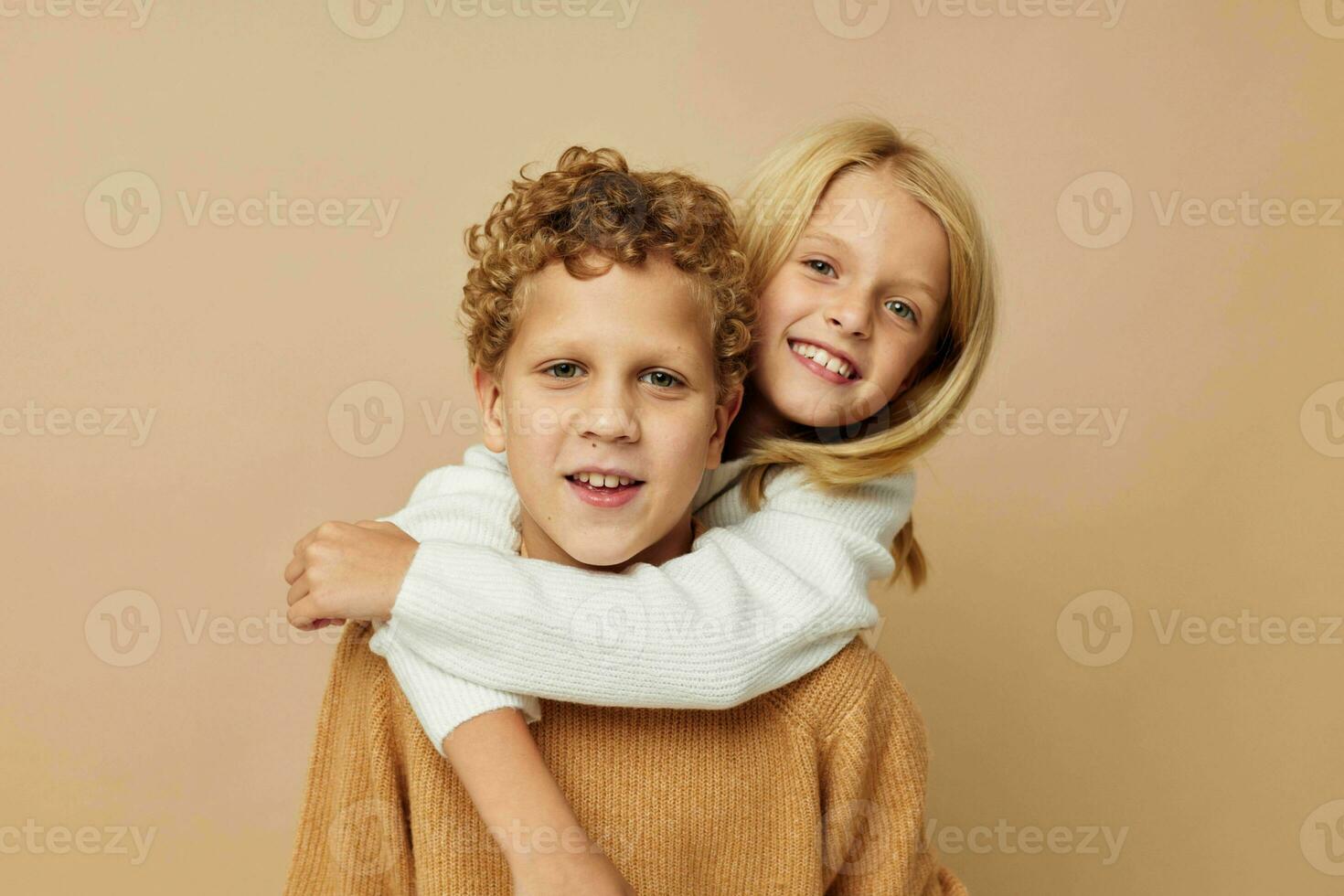 Boy and girl standing next to posing emotions beige background photo