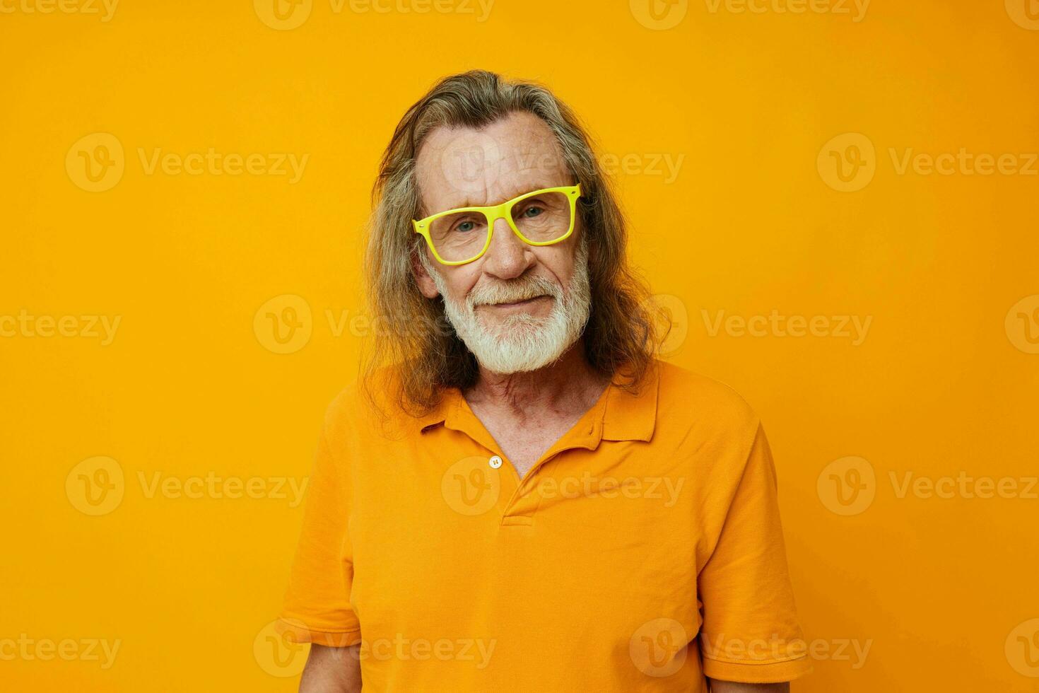 Portrait of happy senior man yellow t-shirt and glasses posing heart-shaped box unaltered photo
