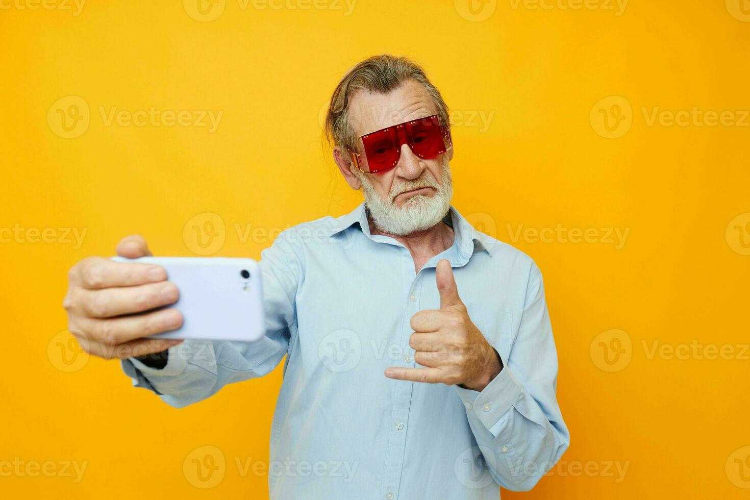 Photo of retired old man blue shirts with glasses takes a selfie isolated background