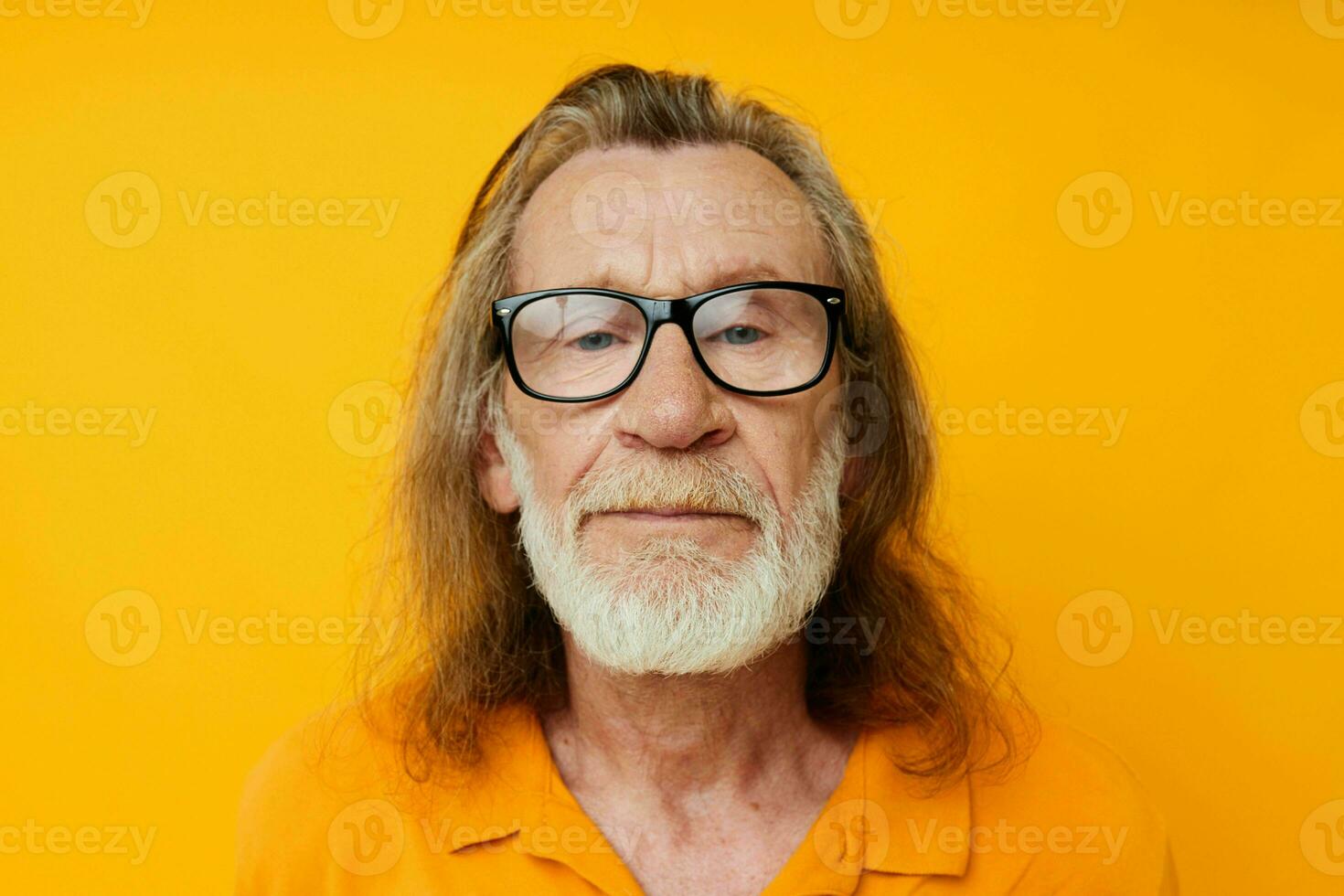 elderly gray-haired man with glasses face close-up yellow background photo