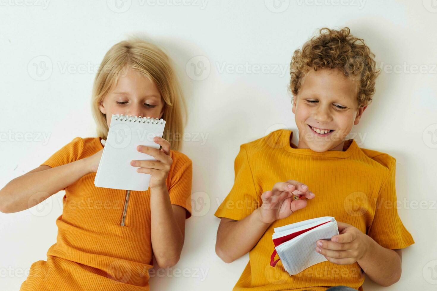 cheerful children lie on the floor with notepads and pencils childhood lifestyle unaltered photo