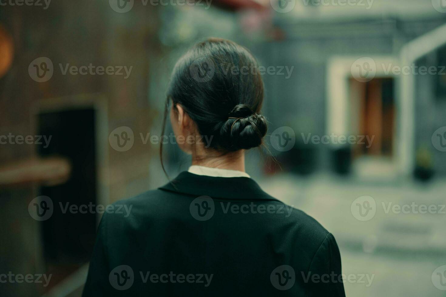 Stylish woman in a black jacket walks along the city street with her back to the camera, follow me photo