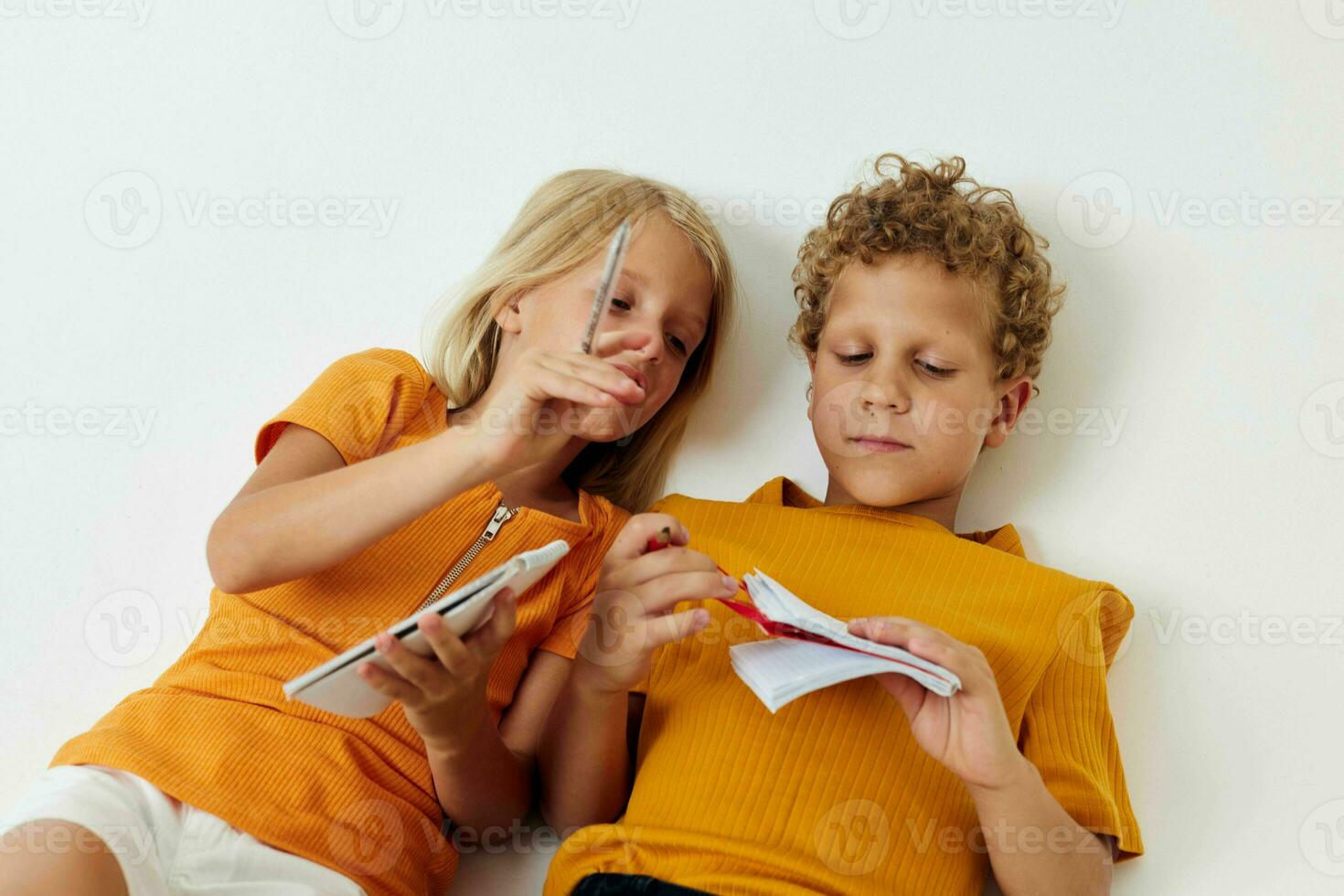 Portrait of cute lie on the floor with notepads and pencils isolated background unaltered photo
