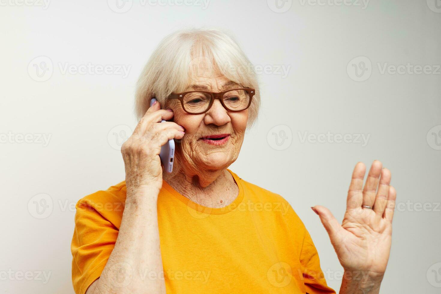 Portrait of an old friendly woman happy lifestyle in yellow t-shirts light background photo