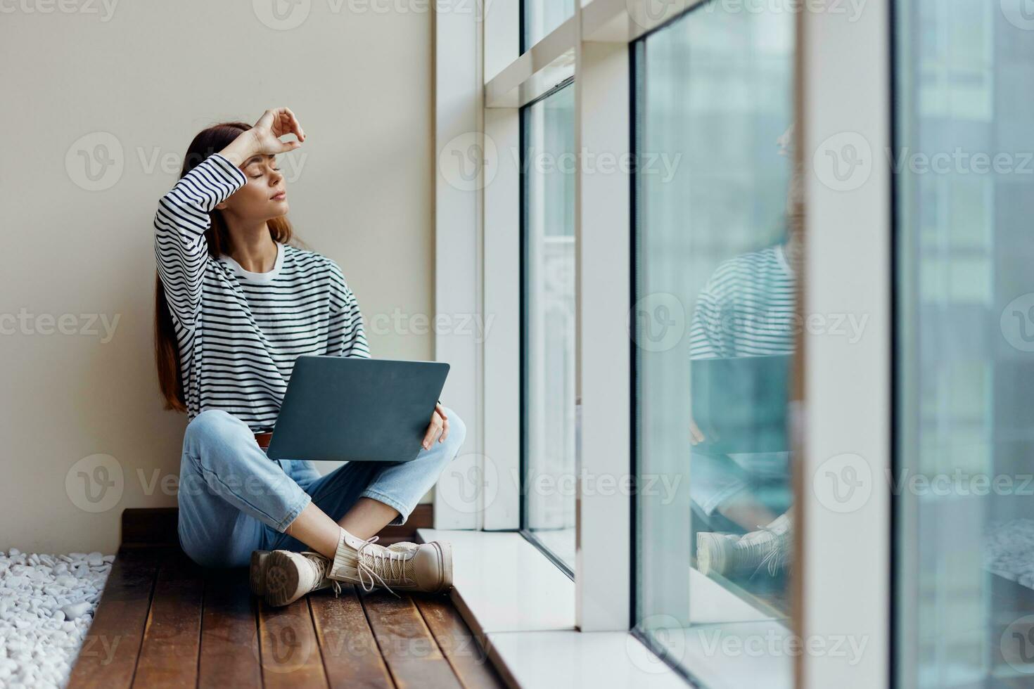 Business woman sitting with a laptop at the window full-length and smiling, happy woman work online in the office, copy space photo