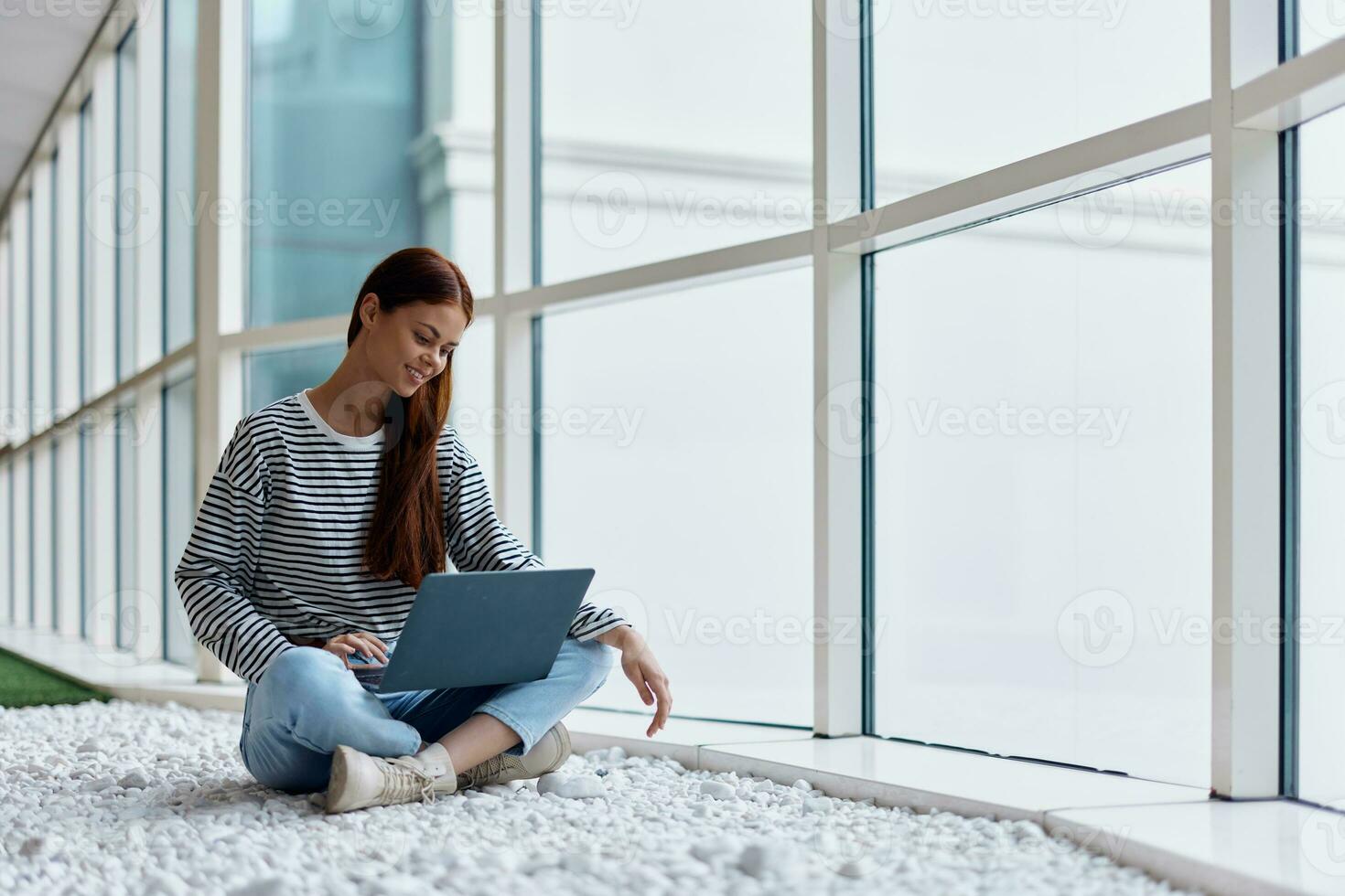 A woman freelancer sits with her laptop near a window overlooking the city and works online via the Internet, an online shopping concept, a copying place photo