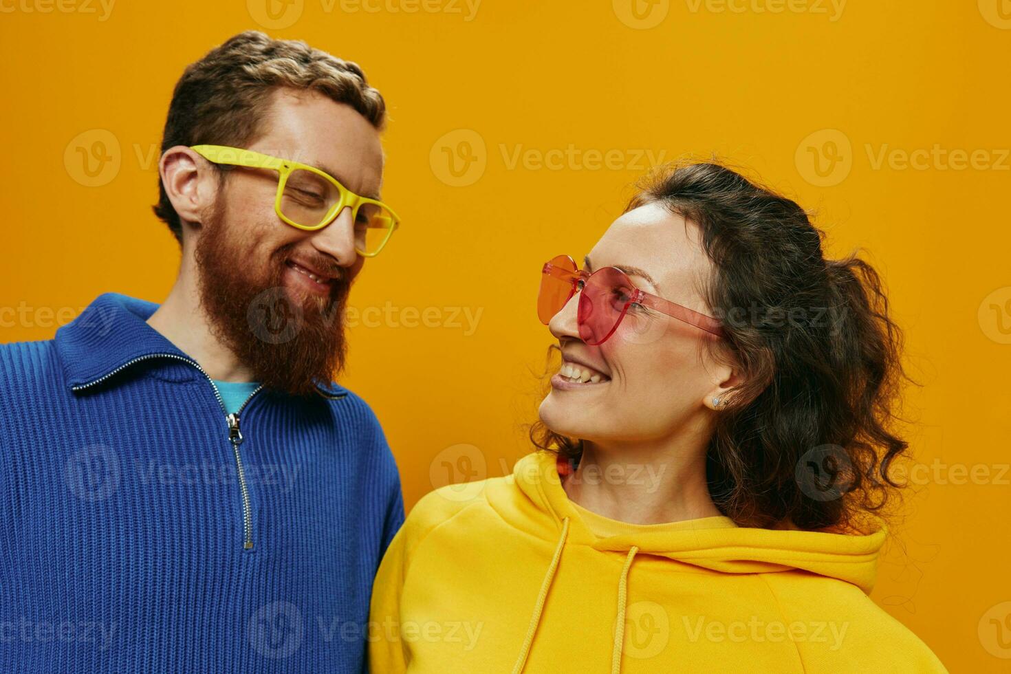 Man and woman couple smiling cheerfully and crooked with glasses, on yellow background, symbols signs and hand gestures, family shoot, newlyweds. photo