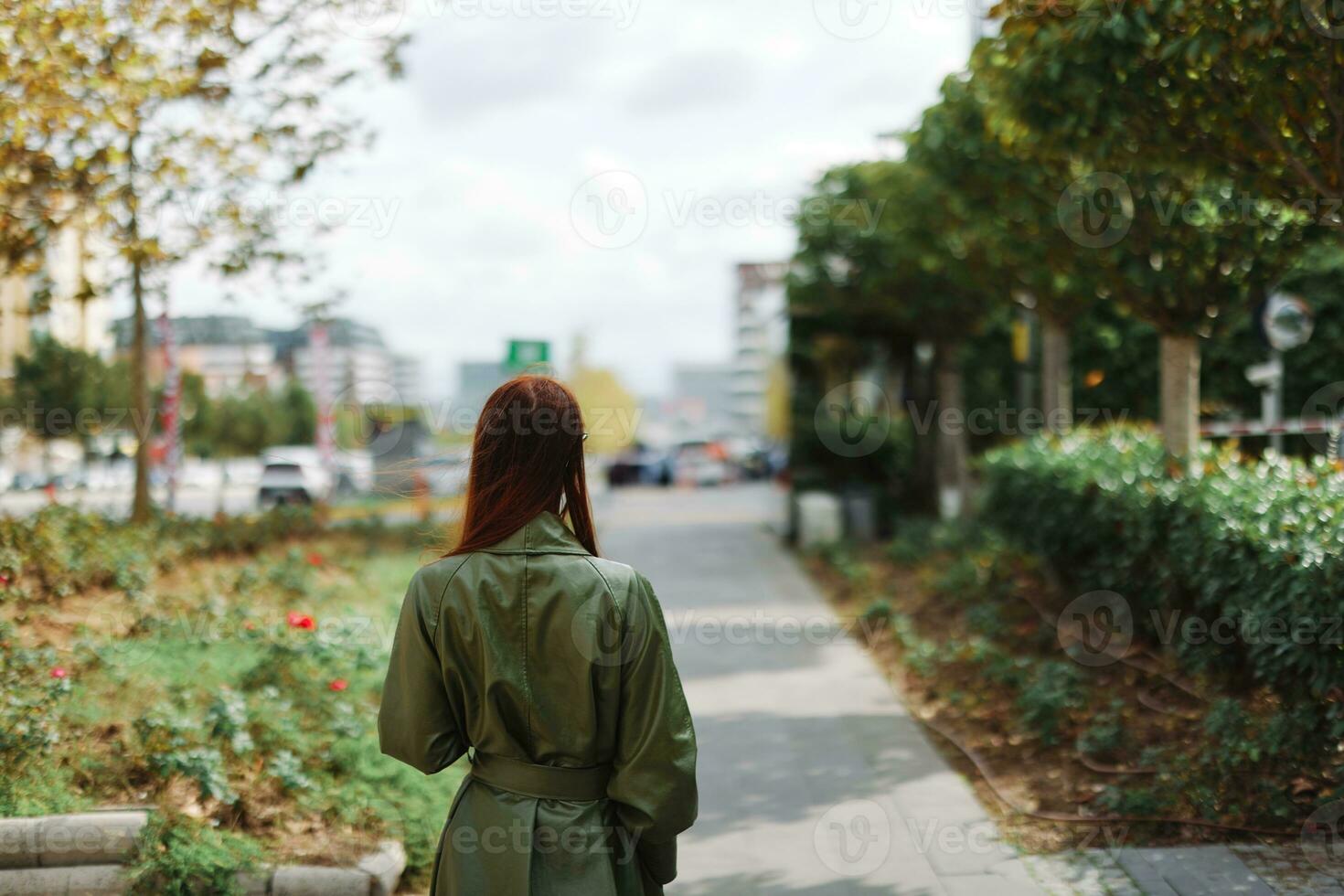 A woman walks around the city from behind in a stylish raincoat photo