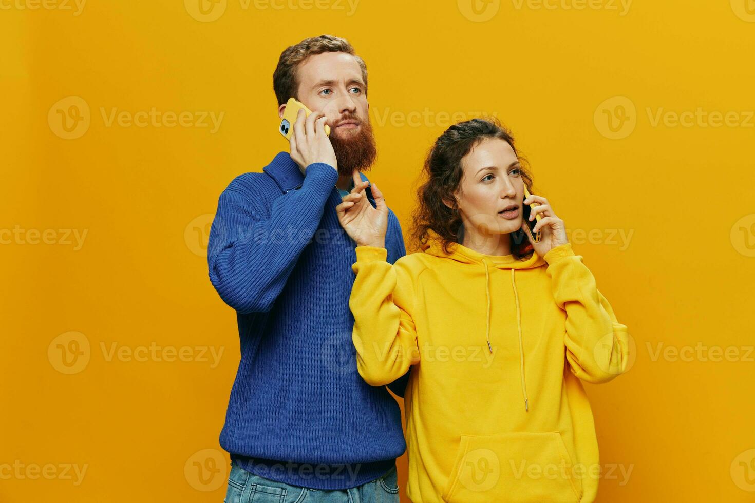 Woman and man cheerful couple with phones in hand talking on cell phone crooked smile cheerful, on yellow background. The concept of real family relationships, talking on the phone, work online. photo