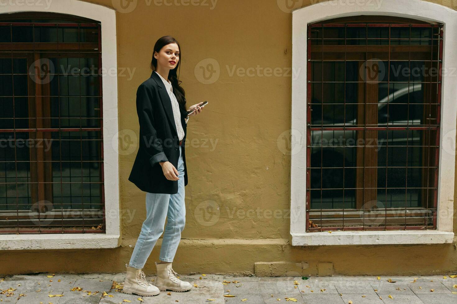 Woman blogger smile with teeth with a phone in her hands walks around the city fashion on the street, spring travel, vacation in the city tourist freelancer, mobile communication and internet for work photo