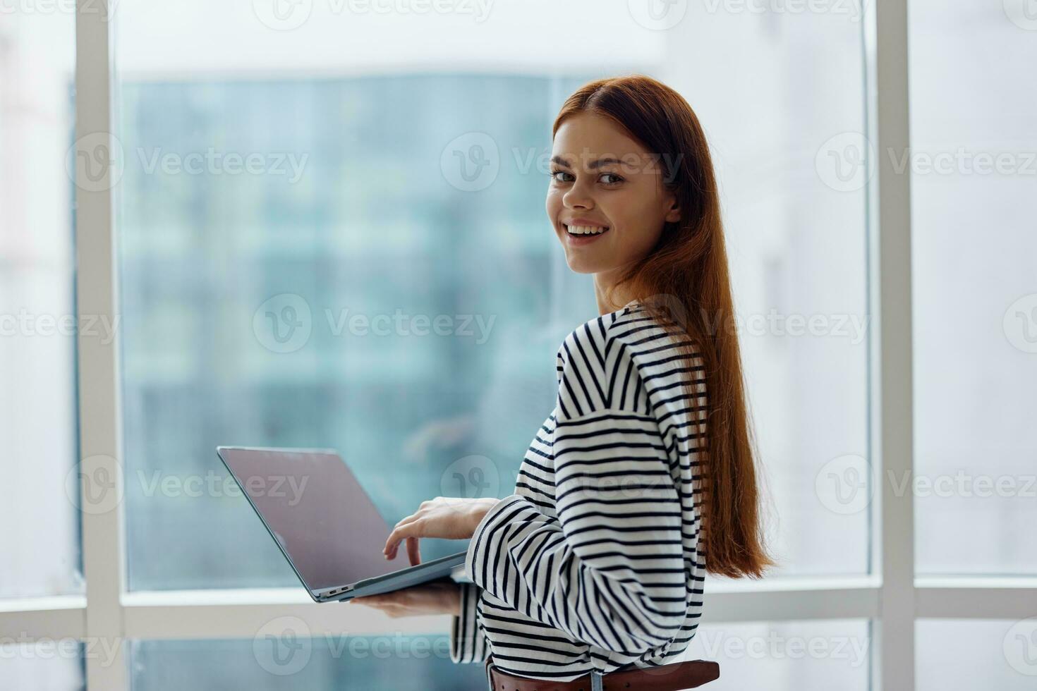 Business woman freelancer working in the city near a window and holding a laptop, working with technology online photo