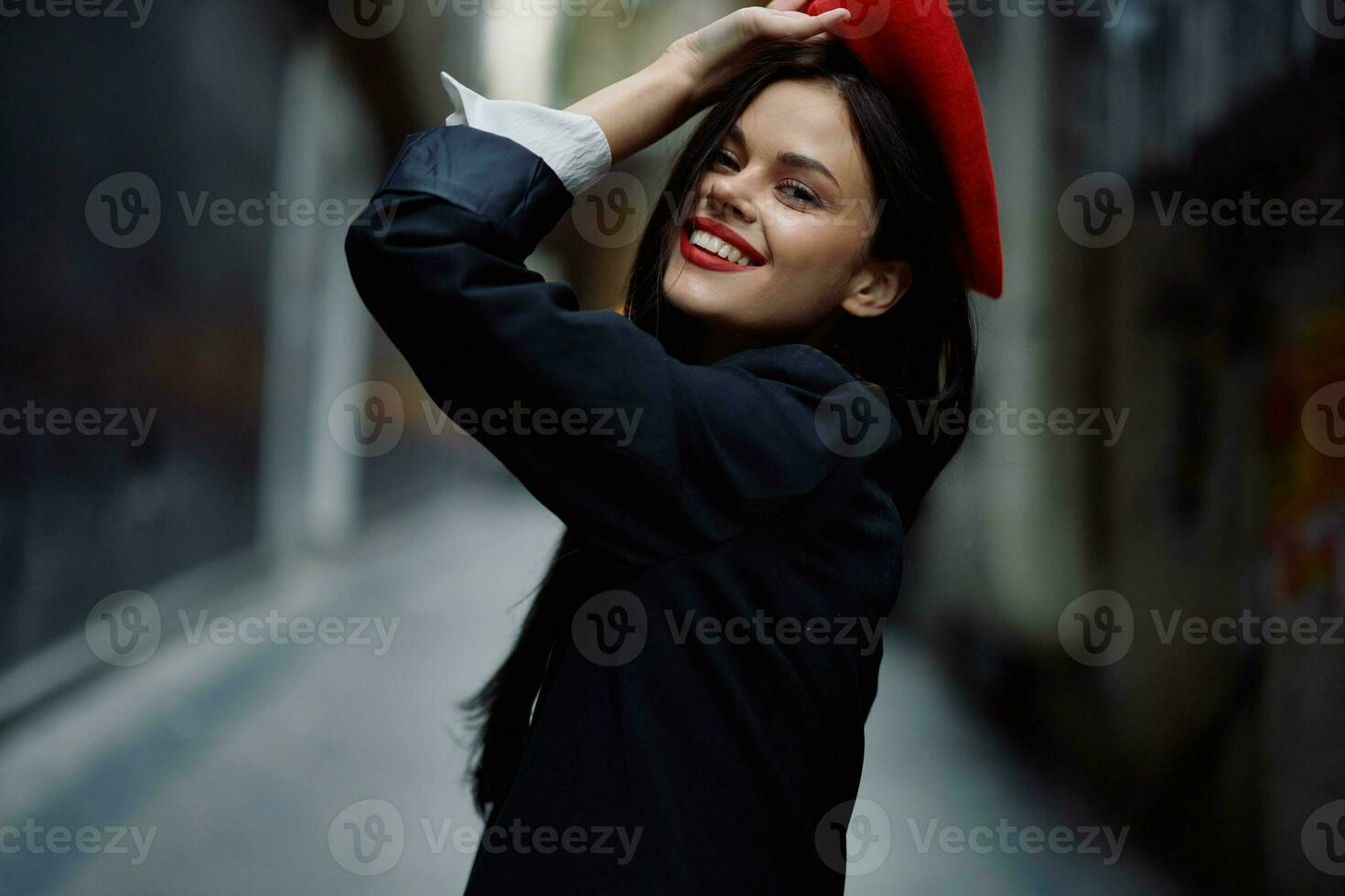 Fashion woman smile with teeth and fun tourist in stylish clothes in jacket and red beret walking down narrow city street flying hair, travel, French style, cinematic color, retro vintage style. photo