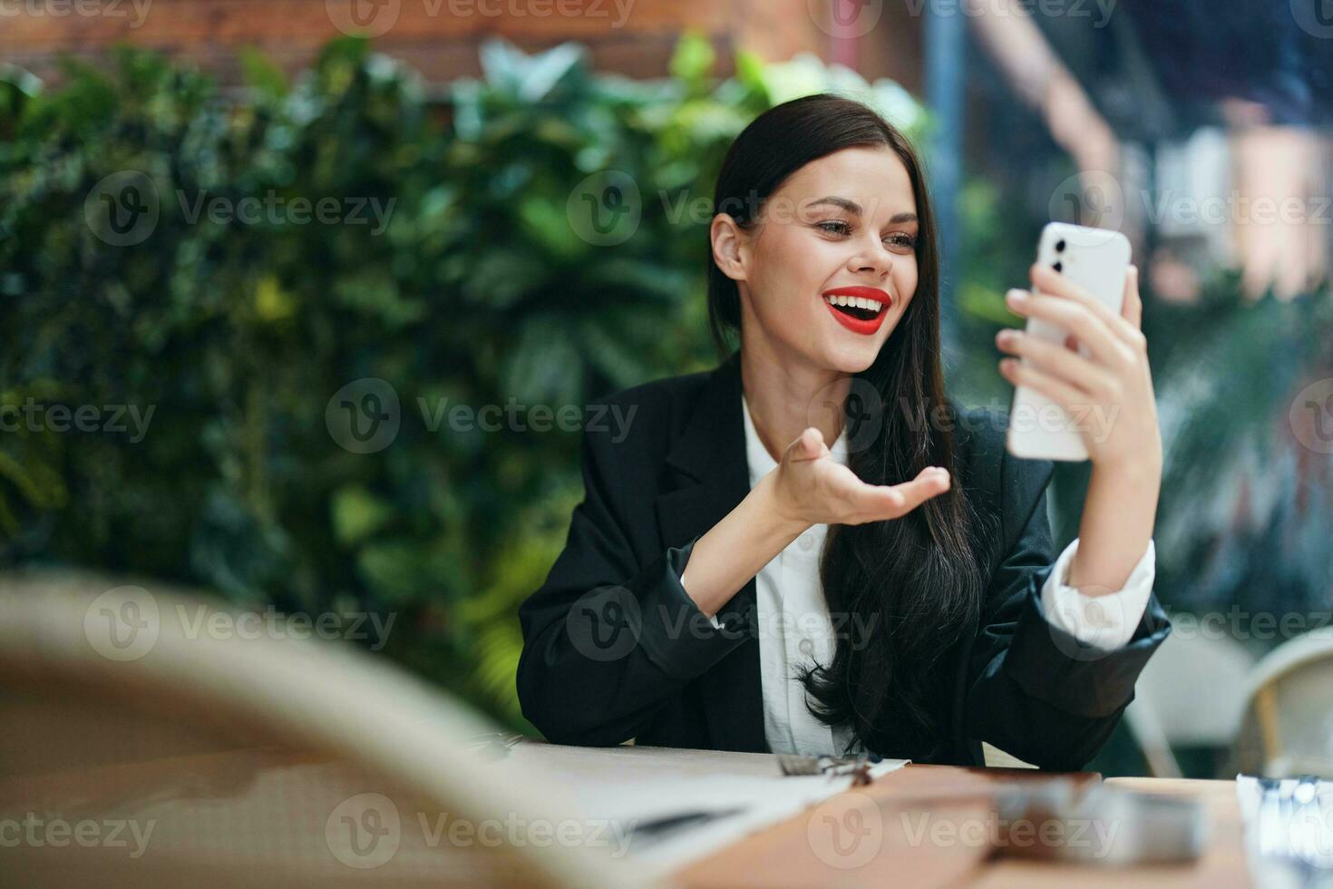 Stylish woman blogger tourist sits in a cafe with a phone in her hands reads a message, mobile communication and internet on a journey, video call, freelance work online, smile with teeth photo