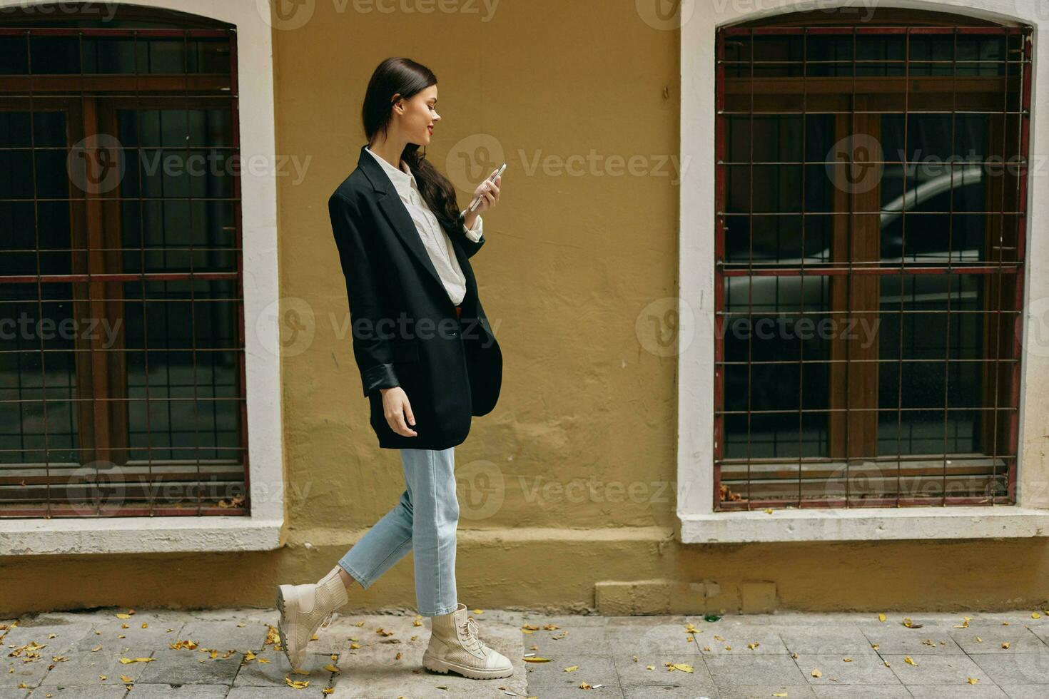 Woman blogger smile with teeth with a phone in her hands walks around the city fashion on the street, spring travel, vacation in the city tourist freelancer, mobile communication and internet for work photo