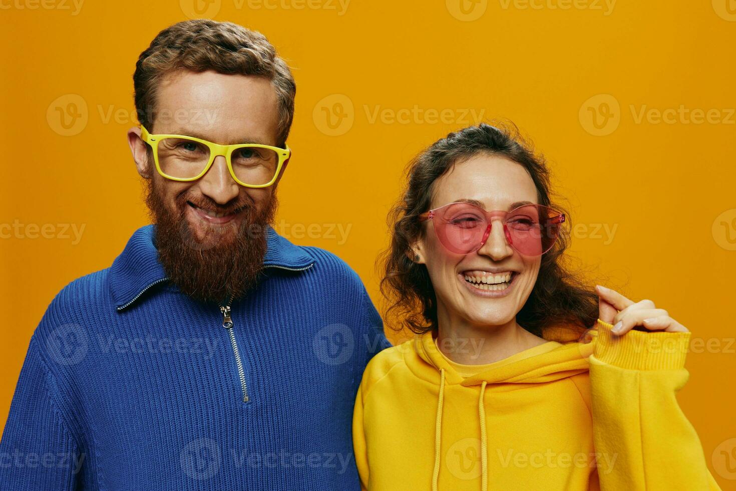 Man and woman couple smiling cheerfully and crooked with glasses, on yellow background, symbols signs and hand gestures, family shoot, newlyweds. photo