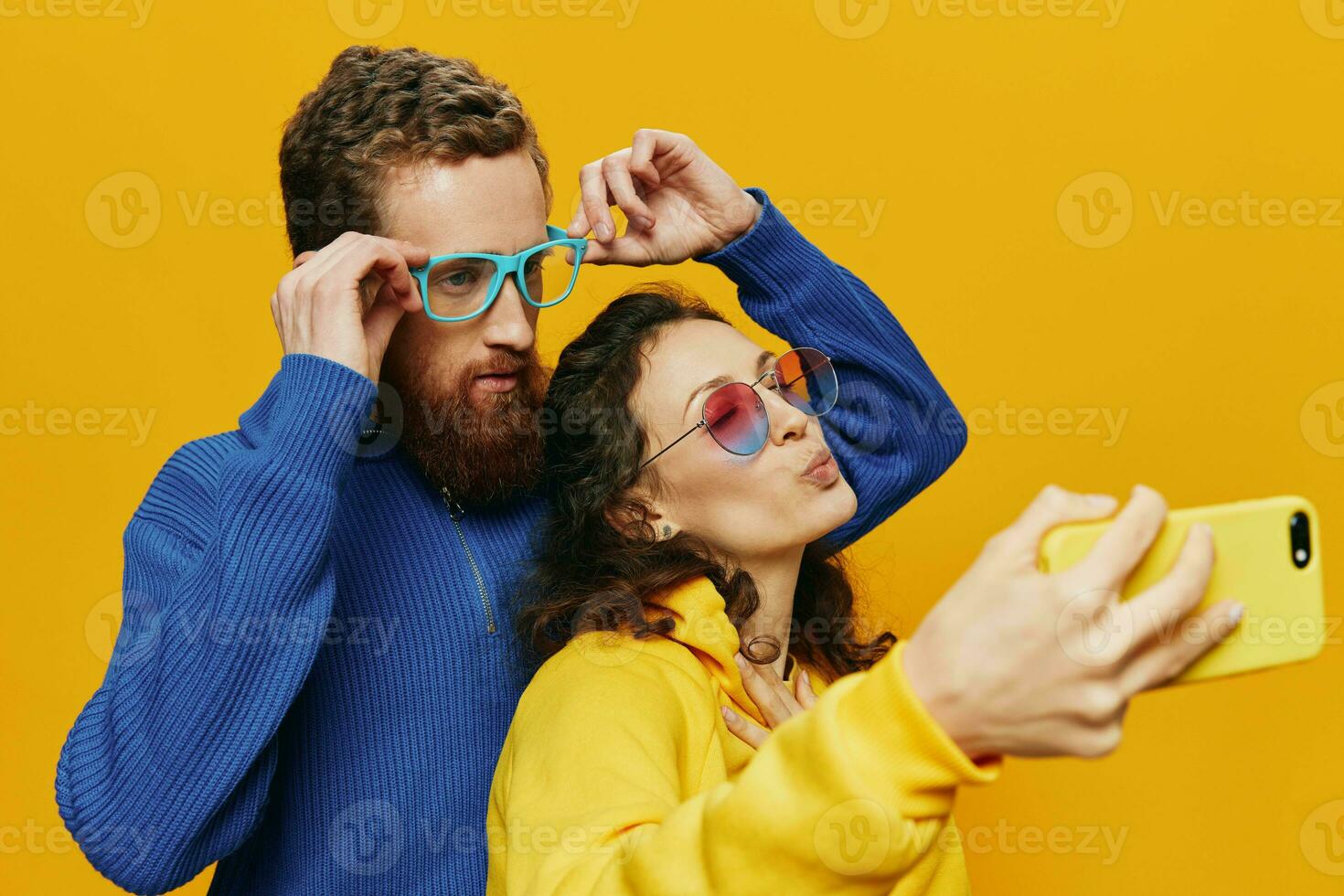 Woman and man funny couple with phones hand social networking and communication crooked do selfies smile fun, on yellow background. The concept of real family relationships, freelancers, work online. photo