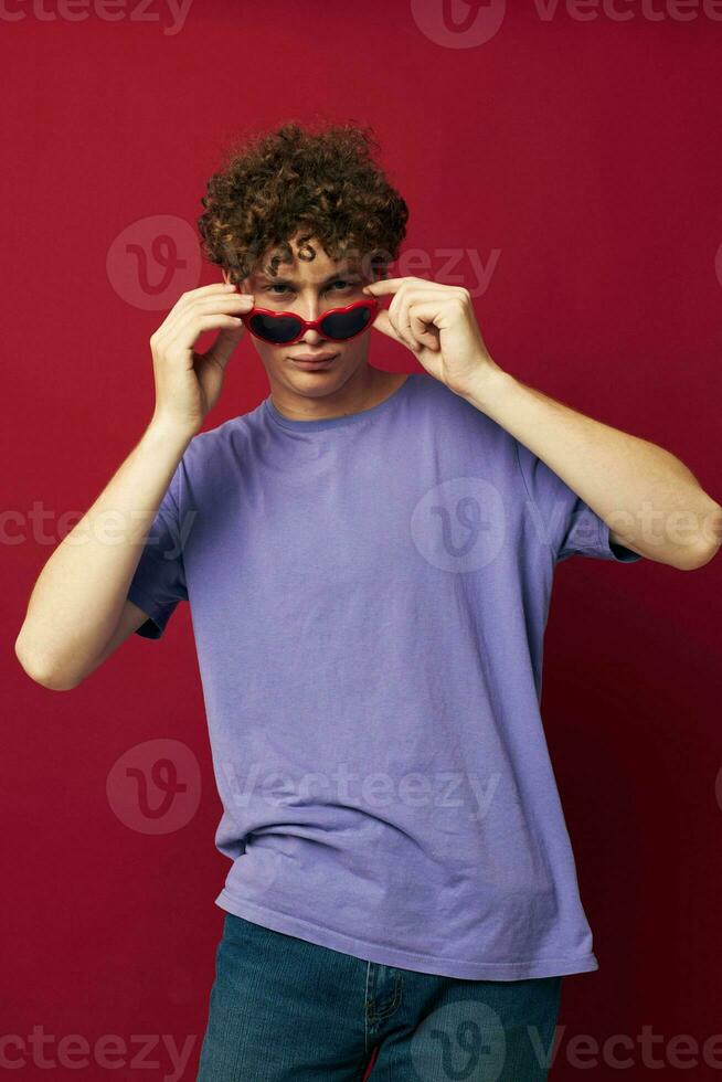 chico con rojo Rizado pelo mano gestos corazón conformado lentes posando aislado antecedentes foto