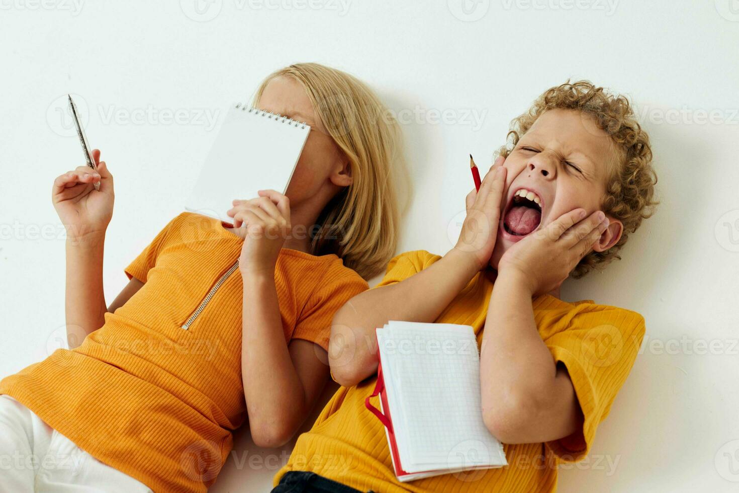 Boy and girl lie on the floor with notepads and pencils childhood lifestyle unaltered photo