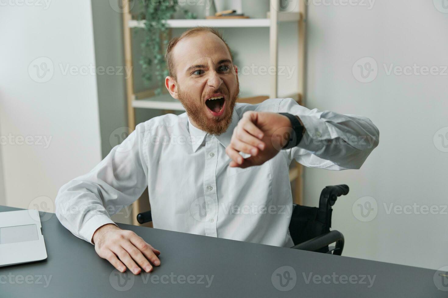 A man wheelchair, a businessman in an office at a laptop, fatigue and emotional burnout at the end of the working day, the concept of working a person with disabilities, freedom from social frameworks photo